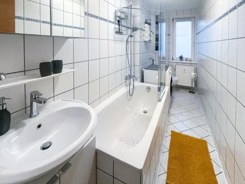 a white bathroom with a tub and a sink at Apartment 54 - Ferienwohnung Bad Arolsen in Bad Arolsen