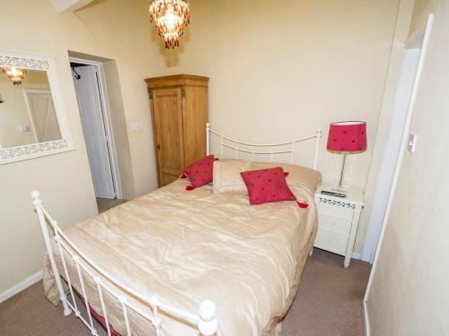 een slaapkamer met een bed met rode kussens erop bij Cobble Cottage30c - Ukc2846 in Blakeney