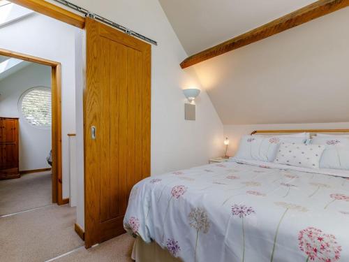 a bedroom with a bed and a wooden door at Acorn Cottage in Knutsford