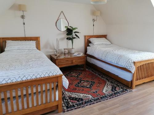 PortmahomackにあるRosslyn Cottageのベッドルーム1室(ベッド2台、テーブル、ラグ付)