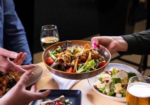 a group of people sitting around a table with a bowl of food at Arawa Park Hotel, Independent Collection by EVT in Rotorua