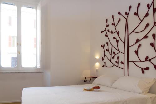 a bedroom with a white bed with a tree on the wall at La Casa Di Iulia in Rome
