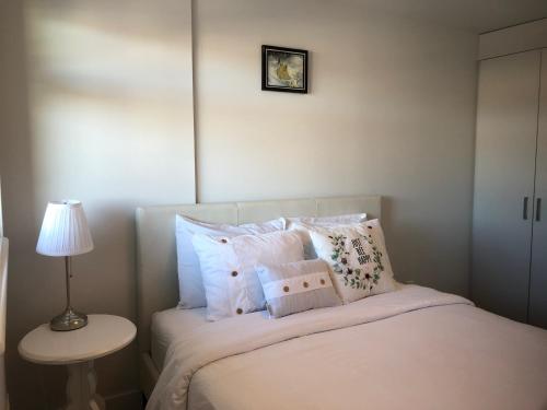 a bedroom with a bed with pillows and a lamp at Amicable, Cozy, High Speed Internet, Sleeps 2 Riverview Downtown Apartment in Calgary