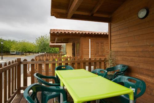 a green table and chairs on a wooden deck at Camping la Sierrecilla in Humilladero