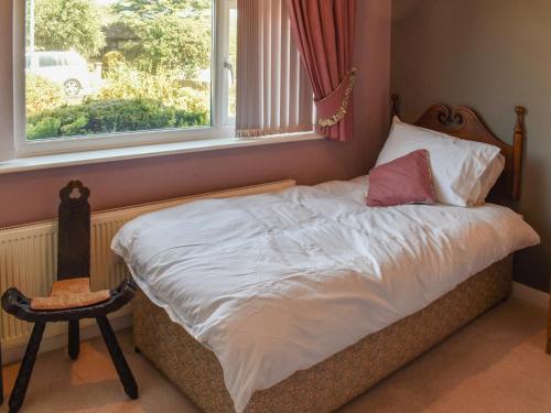 ein Bett in einem Schlafzimmer mit einem Fenster und einem Stuhl in der Unterkunft Squires Bungalow in Gunton