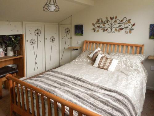 a bedroom with a wooden bed with white sheets at Birkenhead Cottage in Hebden Bridge