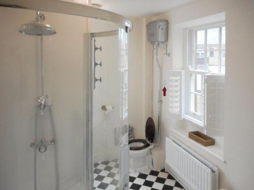 een badkamer met een douche, een toilet en een raam bij Birkenhead Cottage in Hebden Bridge