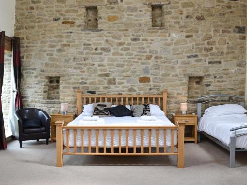 a bedroom with two beds and a brick wall at The Farm House in Wolsingham