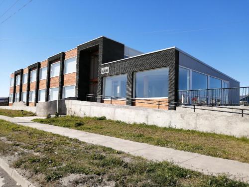 a black building with a sidewalk in front of it at Hotel Costanera in Puerto Natales