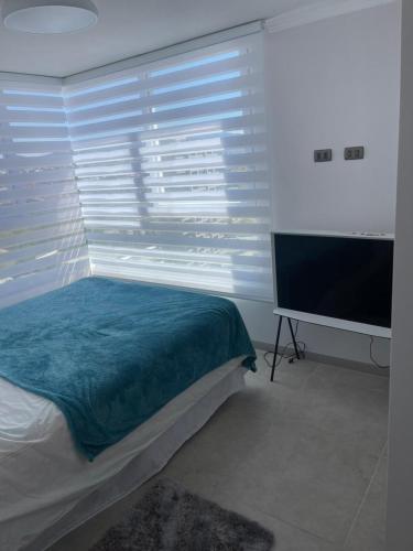 a bedroom with a bed and a large window with a television at Depto Marina Costa a pasos de ENJOY in Coquimbo