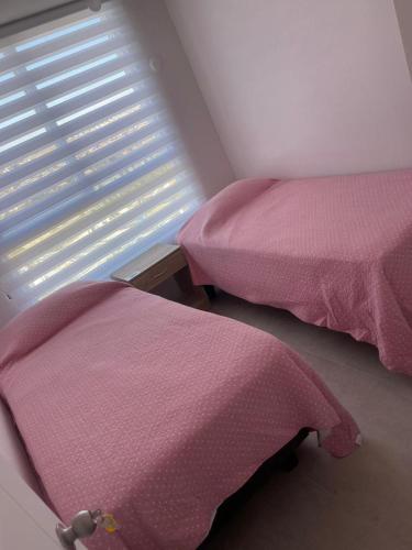 a bedroom with two beds and a window with pink sheets at Depto Marina Costa a pasos de ENJOY in Coquimbo