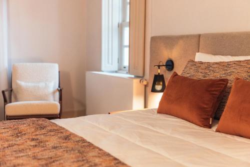 a bedroom with a bed with a chair and a window at Casa da Ribeira in Marco de Canavezes