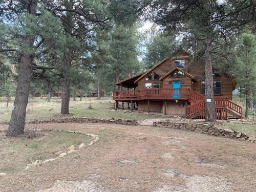a log cabin with a large deck in the woods at Monroe’s Chateau with Hot Tub in Angel Fire
