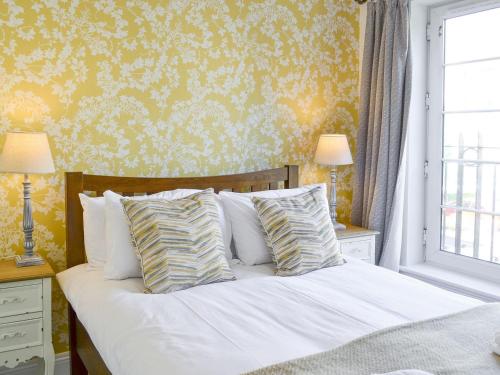 a bedroom with a white bed with yellow wallpaper at Powderhall Brae in Edinburgh