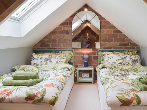 a attic bedroom with two beds and a brick wall at The Chapel Barn in Llangynllo