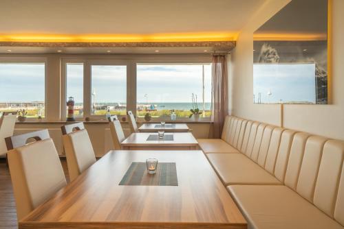a dining room with a table and chairs and windows at Hotel Hochseeinsel in Helgoland