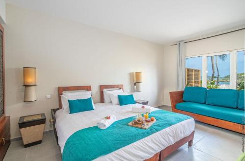 a bedroom with a bed and a blue couch at Villa Maorie 5 chambres avec piscine privée in Le François
