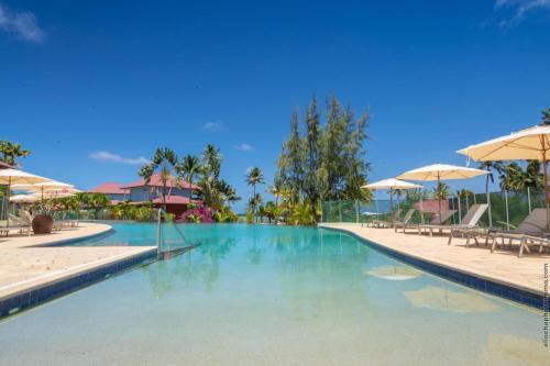 a swimming pool with blue water and umbrellas at Villa Maorie 5 chambres avec piscine privée in Le François
