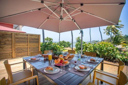 a dining table with an umbrella on a patio at Villa Maorie 5 chambres avec piscine privée in Le François