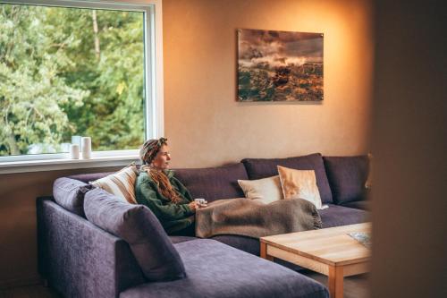 a woman sitting on a couch in a living room at Midt i Lofoten in Alstad
