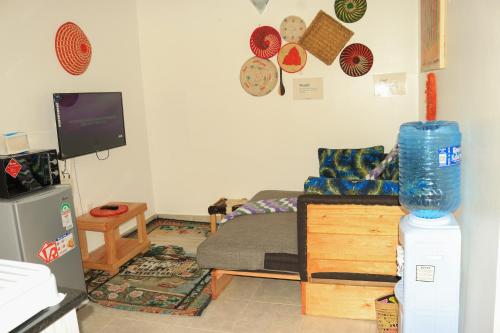 a living room with a bed and a tv at Nook-HeArt Stays in Kakamega