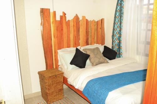 a bedroom with a bed with a wooden headboard at Nook-HeArt Stays in Kakamega