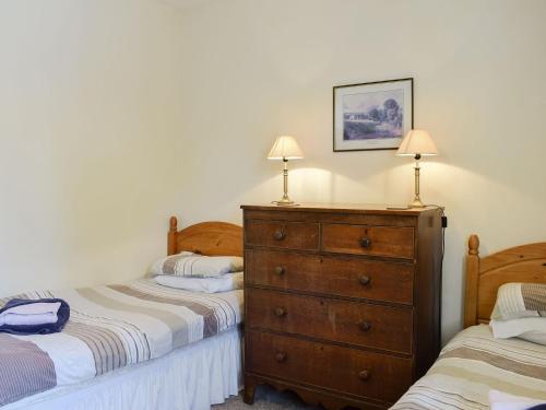 a bedroom with two beds and a dresser at Grisedale Coach House in Threshfield