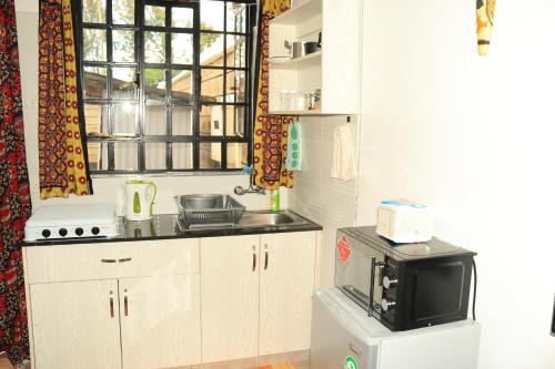 a small kitchen with a microwave and a television at Nook-HeArt Stays in Kakamega