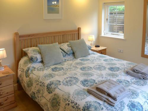 a bedroom with a large bed with a floral bedspread at Tresidder Barn in Constantine