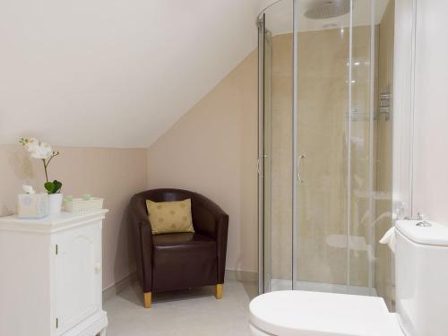 a bathroom with a shower and a chair and a toilet at Gardeners Lodge in Pembroke