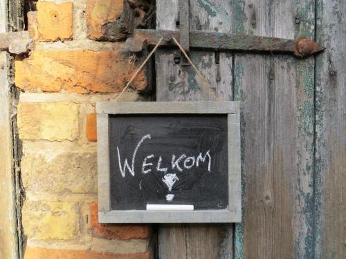 una señal colgando de una pared de ladrillo con la palabra bienvenida en Holiday Home 't Hof der Witte Damen, en Veurne