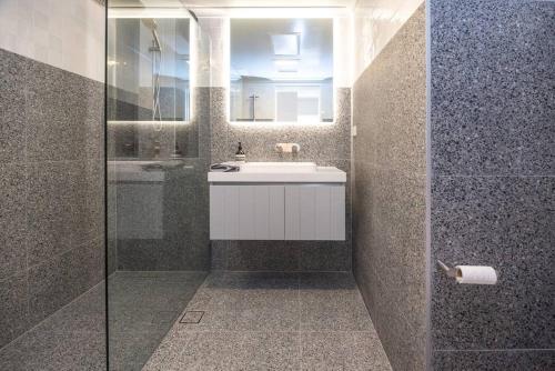 a bathroom with a tub and a sink and a mirror at Luxury modern CBD ground floor apartment. in Canberra