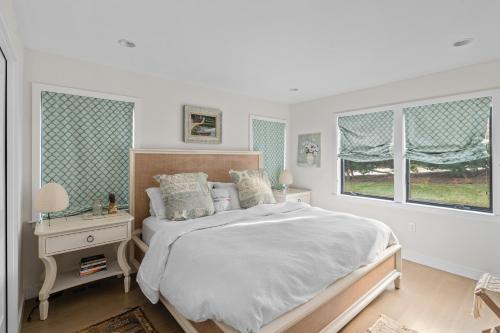 a white bedroom with a bed and two windows at La Sirena in Montauk