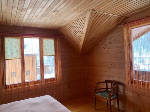 a bedroom with a bed and a chair and windows at Chalet TysaBorkut in Kvasy