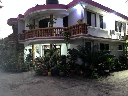 Cette grande maison blanche dispose d'un balcon et de plantes. dans l'établissement Stay In Style Lodge, à Dar es Salaam