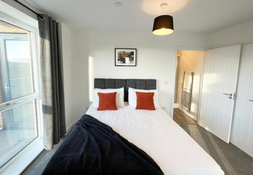 a bedroom with a large white bed with red pillows at Riverside Apartment Chelmsford in Chelmsford