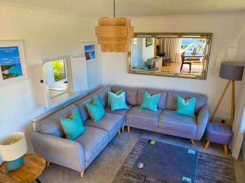 a living room with a blue couch and a mirror at Spacious home with panoramic sea view, free parking EV & large garden in Mousehole