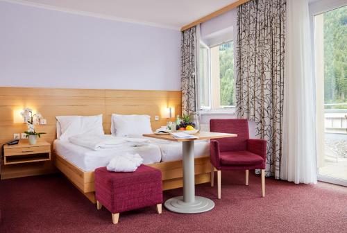 バート・ザンクト・レオンハルト・イム・ラヴァントタールにあるGesundheitsresort Bad St. Leonhardのベッド、テーブル、椅子が備わるホテルルームです。