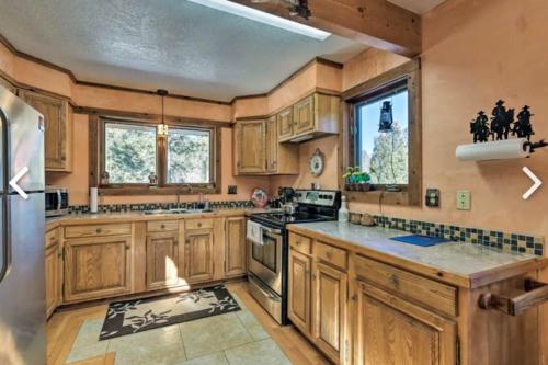 a large kitchen with wooden cabinets and appliances at Raven’s Nest Cabin with Glowing Bocce Ball Court in Angel Fire