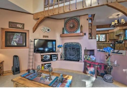 a living room with a fireplace and a tv at Raven’s Nest Cabin with Glowing Bocce Ball Court in Angel Fire