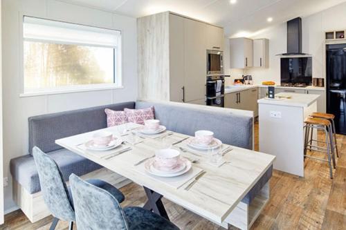 a dining room with a table and a kitchen at Bay Tree Lodge: Lakeside lodge w/hot tub & cinema surround sound in Woodhall Spa