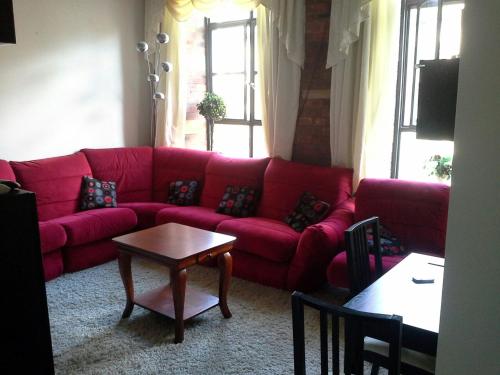 un sofá rojo en una sala de estar con mesa en Lister Mills, Apartment 327, Silk Warehouse, Lilycroft Rd, BD9 5BD en Bradford