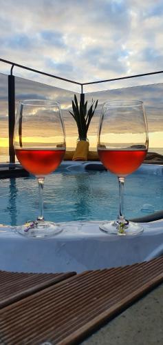 two glasses of wine sitting on a table next to a pool at Casa da Rocha in Paul do Mar
