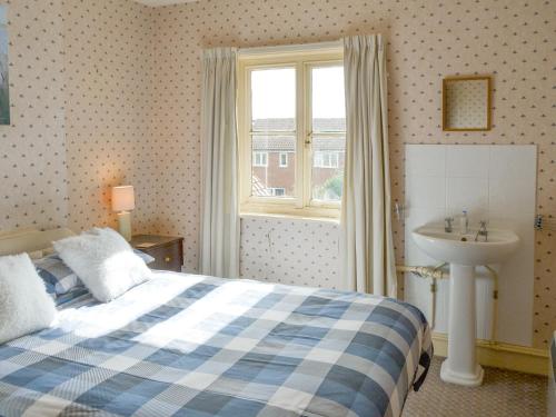 een slaapkamer met een bed, een wastafel en een raam bij The Castaway in Mundesley