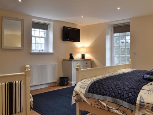 een slaapkamer met een bed en een tv aan de muur bij Gardeners Cottage in Montrose
