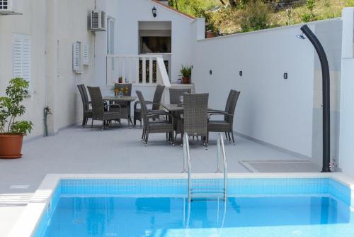 eine Terrasse mit einem Tisch, Stühlen und einem Pool in der Unterkunft Villa Bingo in Cavtat