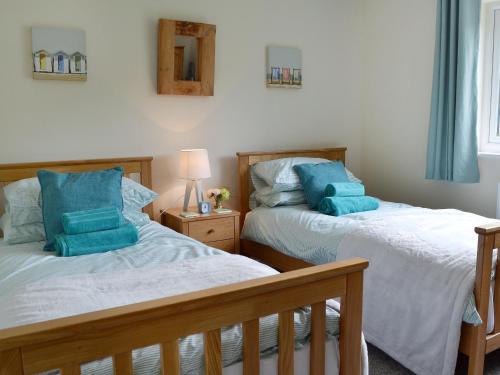 two beds in a bedroom with blue pillows at Cornbrash Farm Cottage in Dallington