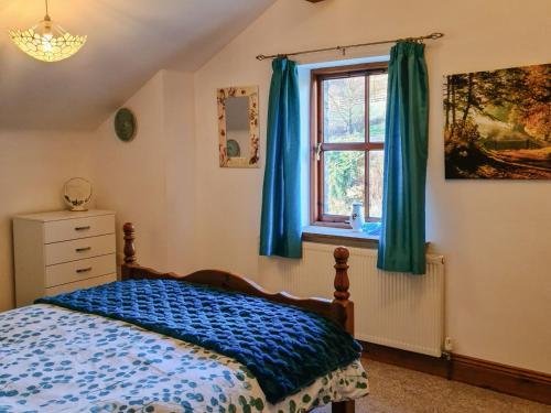 Hollin Bank Cottage في Salterforth: غرفة نوم بسرير ونافذة ذات ستائر زرقاء