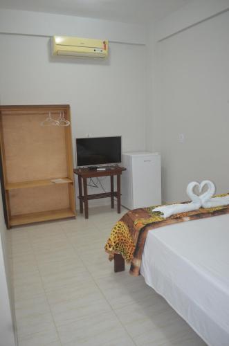 a bedroom with a bed and a tv and a table at Pousada Encantos da Amazônia in Alter do Chao