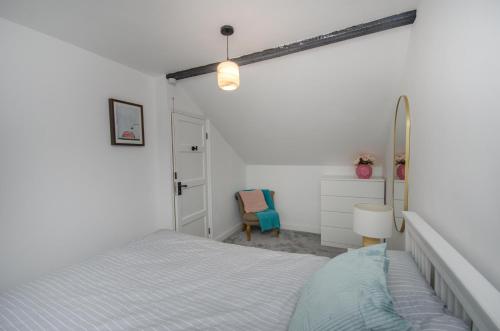 a white bedroom with a bed and a chair at Hideaway Cottage in Bristol